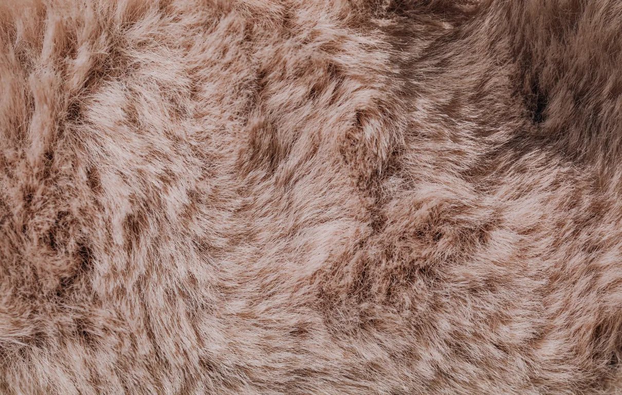 Close-up of soft, plush natural-fiber fabric texture in warm beige tones.